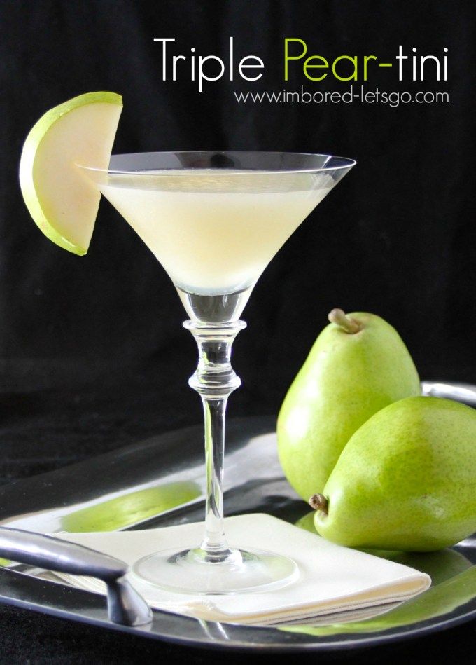 two pears sit on a tray next to a martini glass with an apple slice