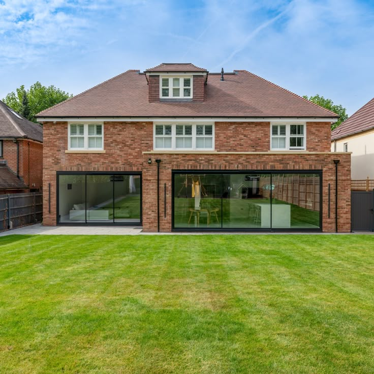 a large brick house with glass doors on the front and side windows in the back