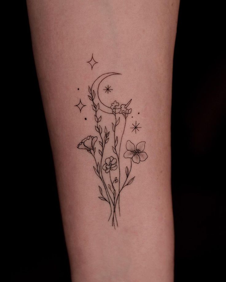 a woman's leg with flowers and a crescent tattoo on the left side of her arm