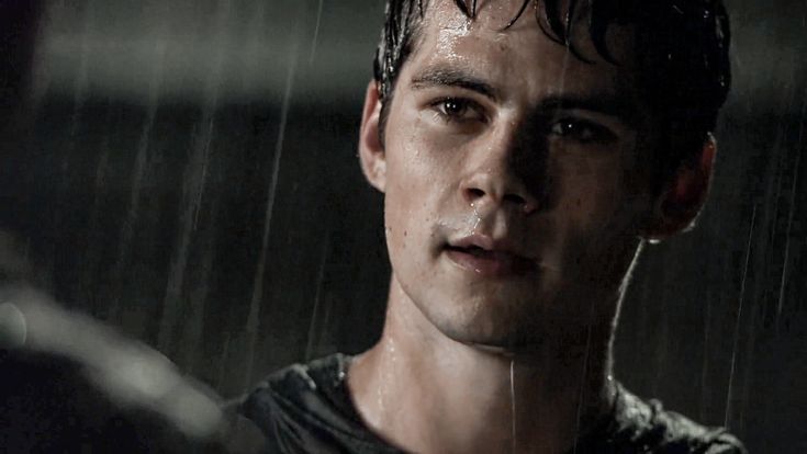 a young man standing in the rain with his eyes closed and looking into the distance