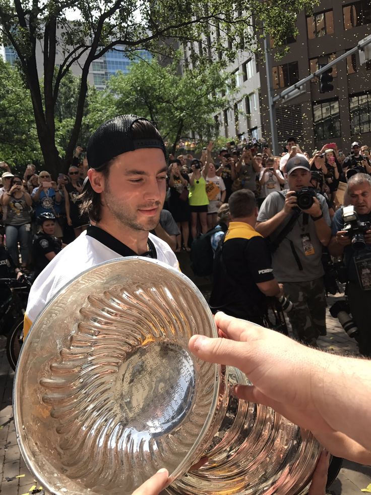 a man holding up a large glass bowl in front of a group of people on the street