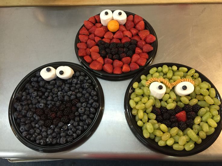 three black bowls filled with fruit shaped like angry birds and berries in the shape of eyes