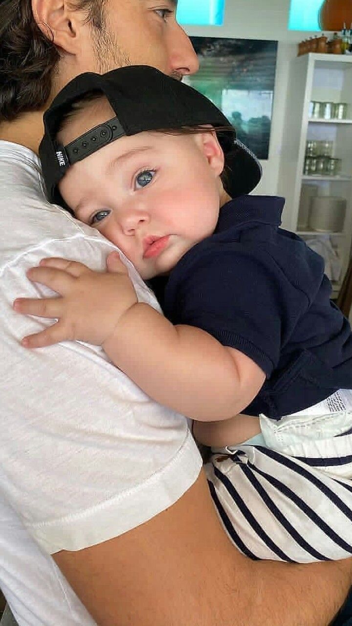 a man holding a baby in his arms and wearing a visor on it's head