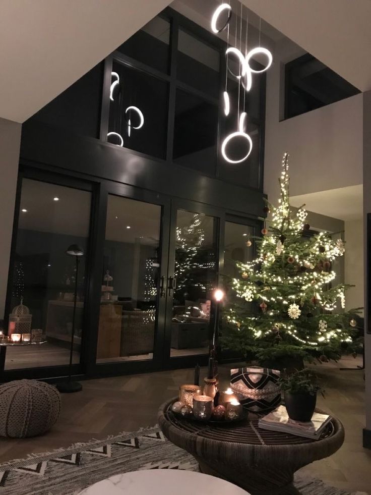 a living room with a christmas tree in the center and lights hanging from the ceiling