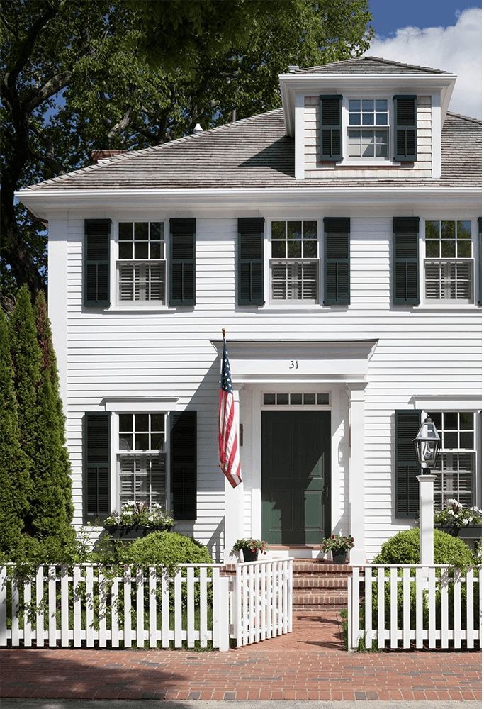 a white house with black shutters and an american flag