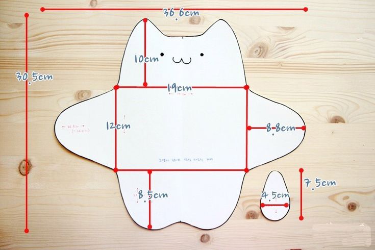 a paper cut out of a cat on top of a wooden table with measurements for it