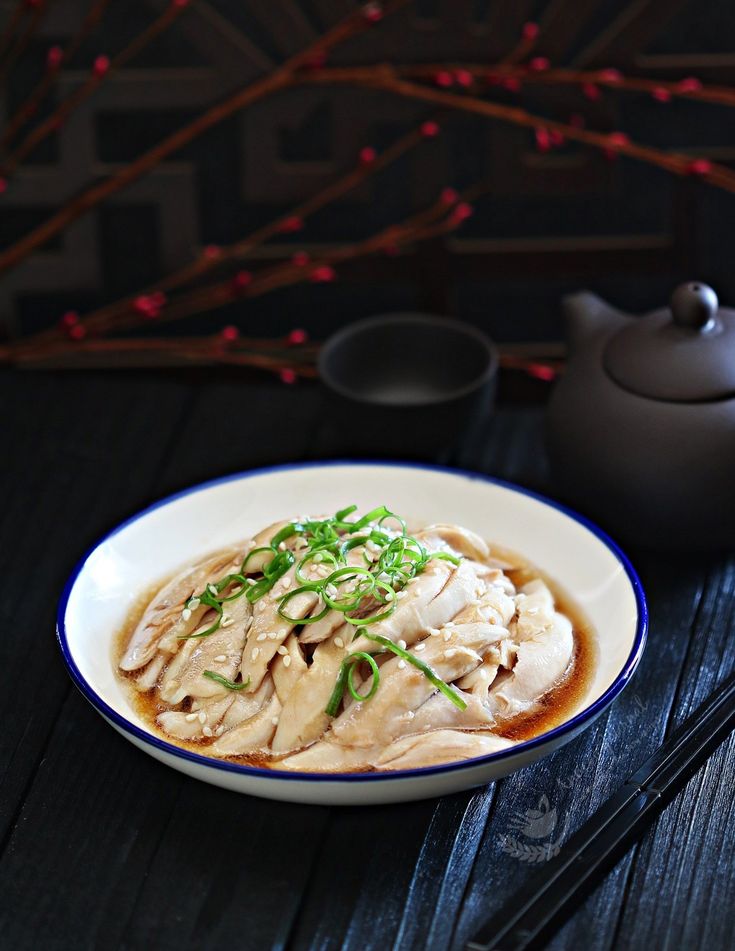 a white bowl filled with food on top of a wooden table next to a teapot