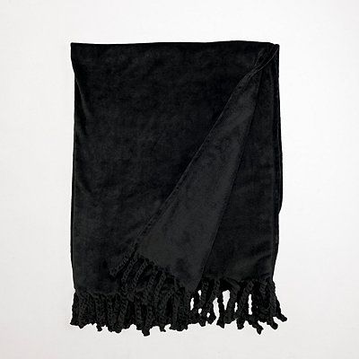 a black towel with fringes hanging on a wall