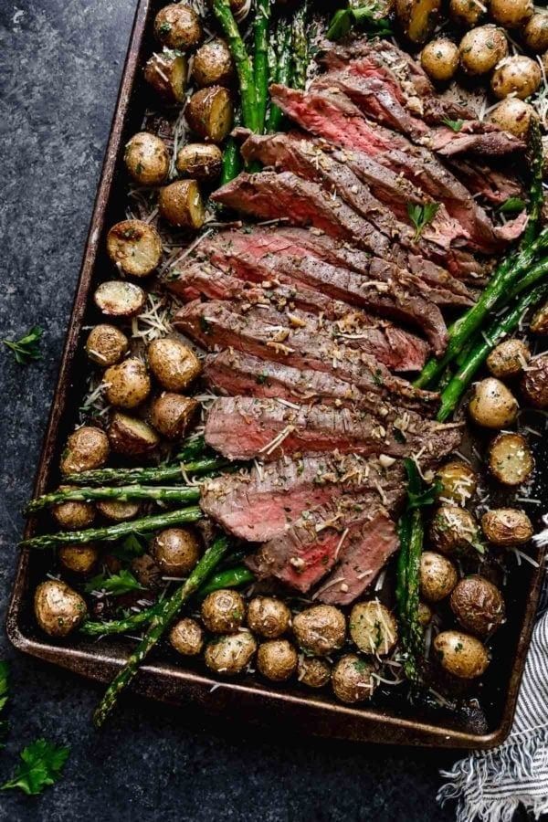 steak, potatoes and asparagus on a baking sheet