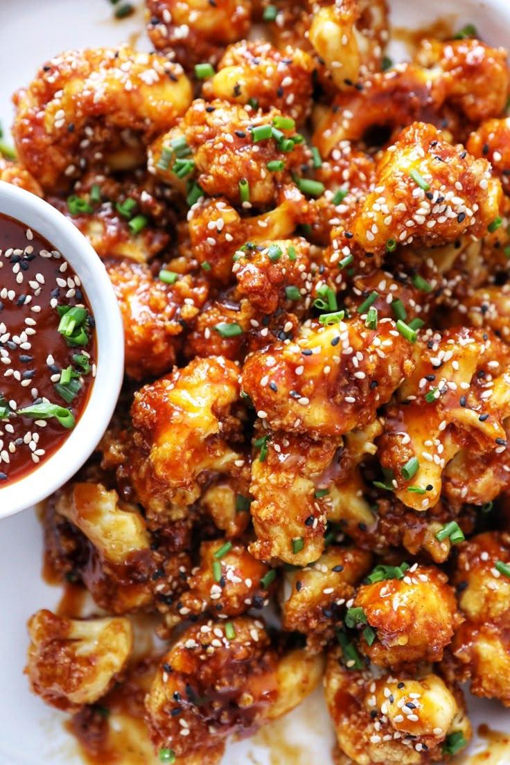 a white plate topped with fried food next to a bowl of ketchup and dipping sauce