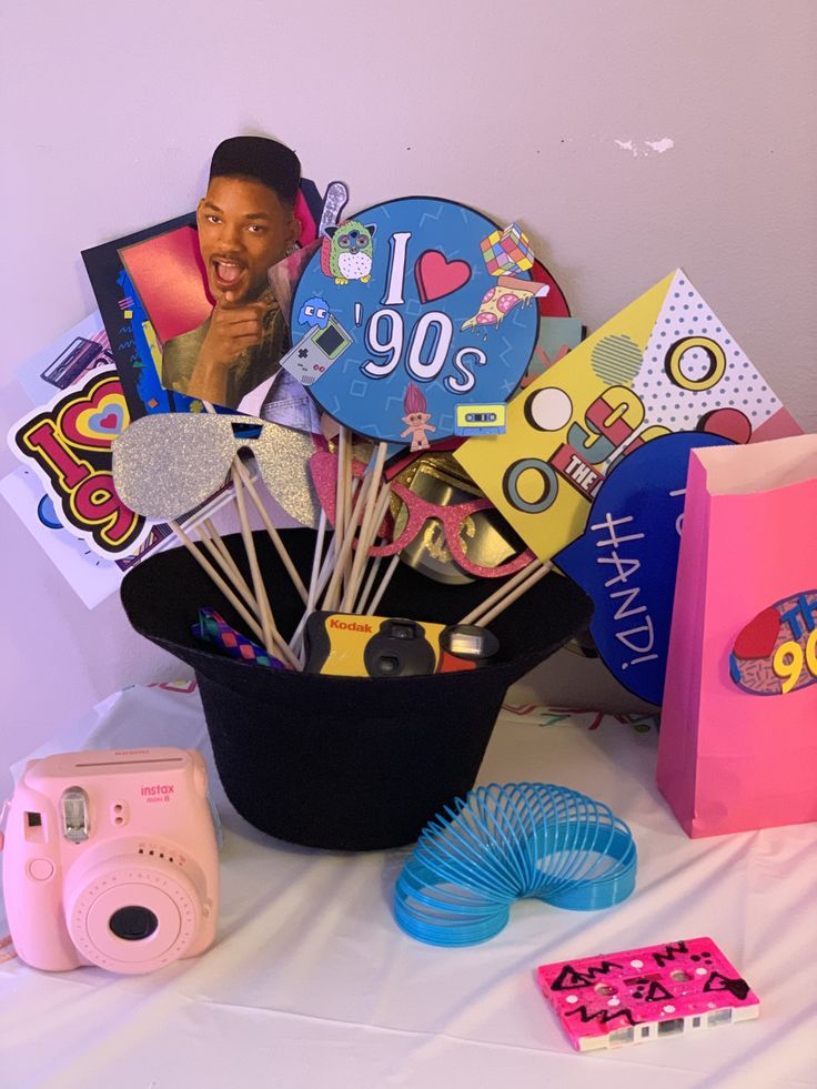 a table topped with lots of assorted items next to a pink polaroid camera