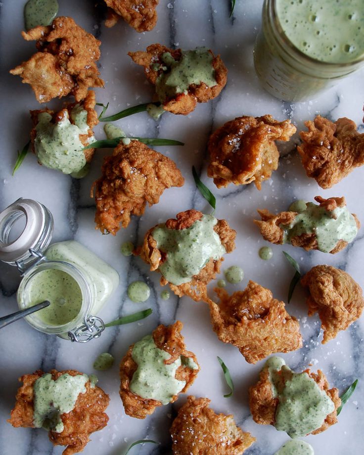 some fried food is sitting on a marble table next to a glass of green liquid