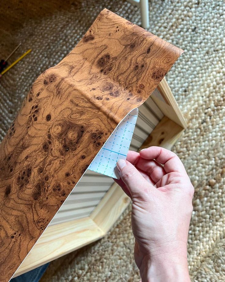 a person holding a piece of wood in their left hand and measuring it with a ruler