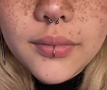 a woman with freckles and piercings on her nose