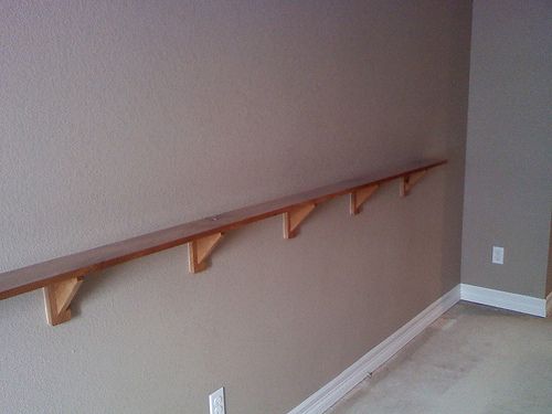 three wooden shelves on the wall in a room with no carpeting or walls to use