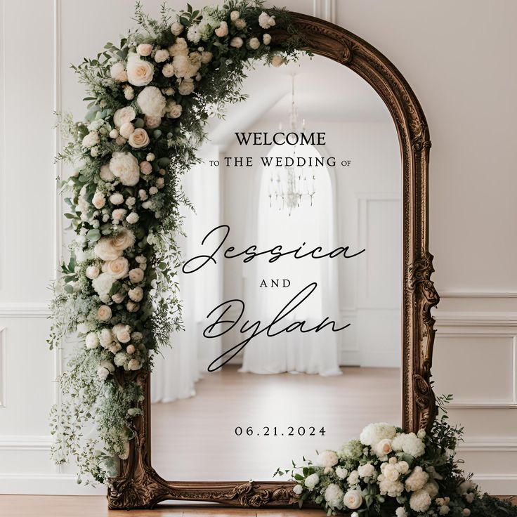 an ornate mirror with flowers and greenery on the frame for a wedding welcome card