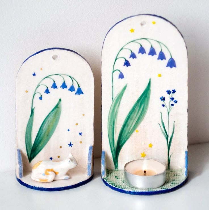 two ceramic candle holders decorated with blue and white flowers, one holding a tea light