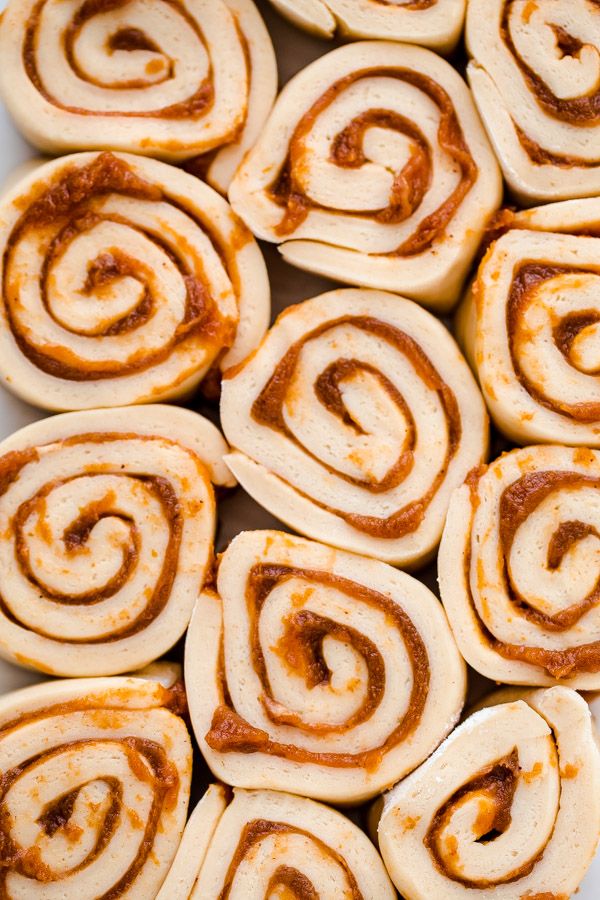 several cinnamon rolls on a white plate with some sauce in the middle and one rolled up