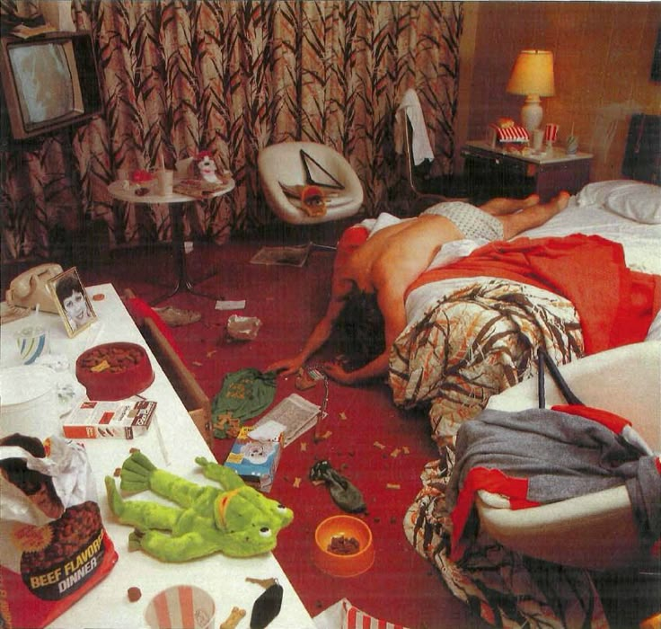 a man is laying on the floor in his bedroom with food and other items scattered around him