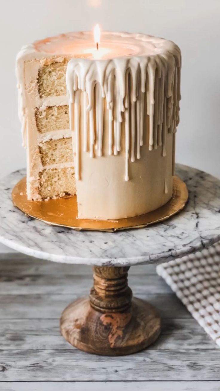 a cake sitting on top of a wooden table with a lit candle in the middle