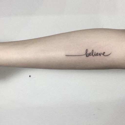 a woman's arm with the word believe written on it and an arrow tattoo