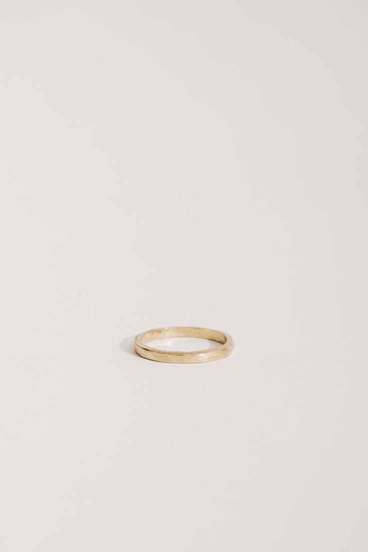 a plain gold wedding ring on a white background