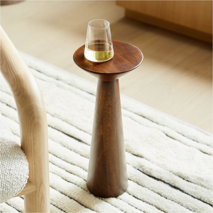 a wooden table with a glass on it and a white rug in the foreground