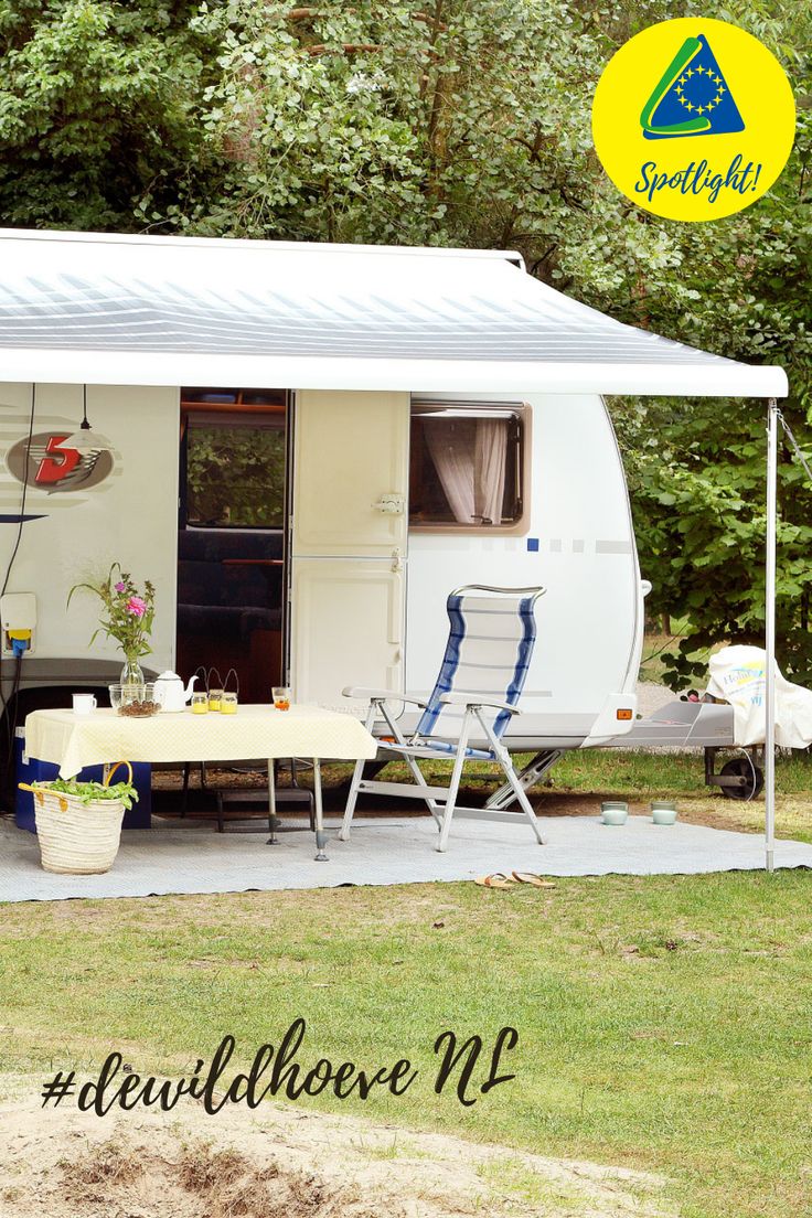 an rv is parked in the grass with its door open and table set up outside