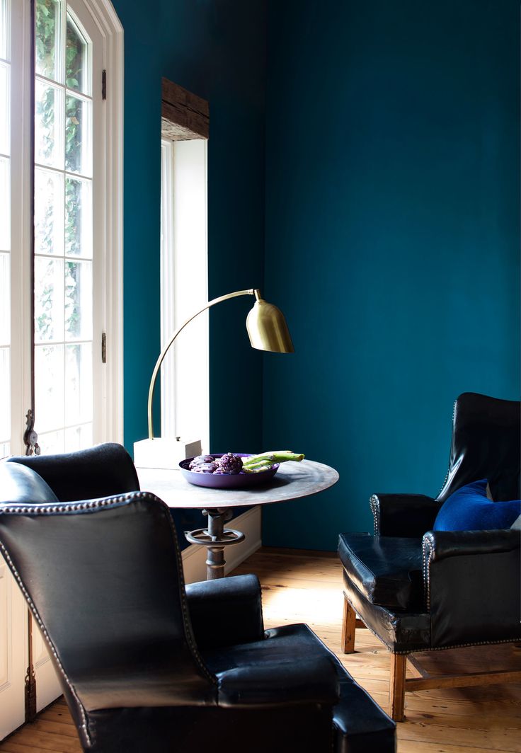 a living room with blue walls and leather chairs