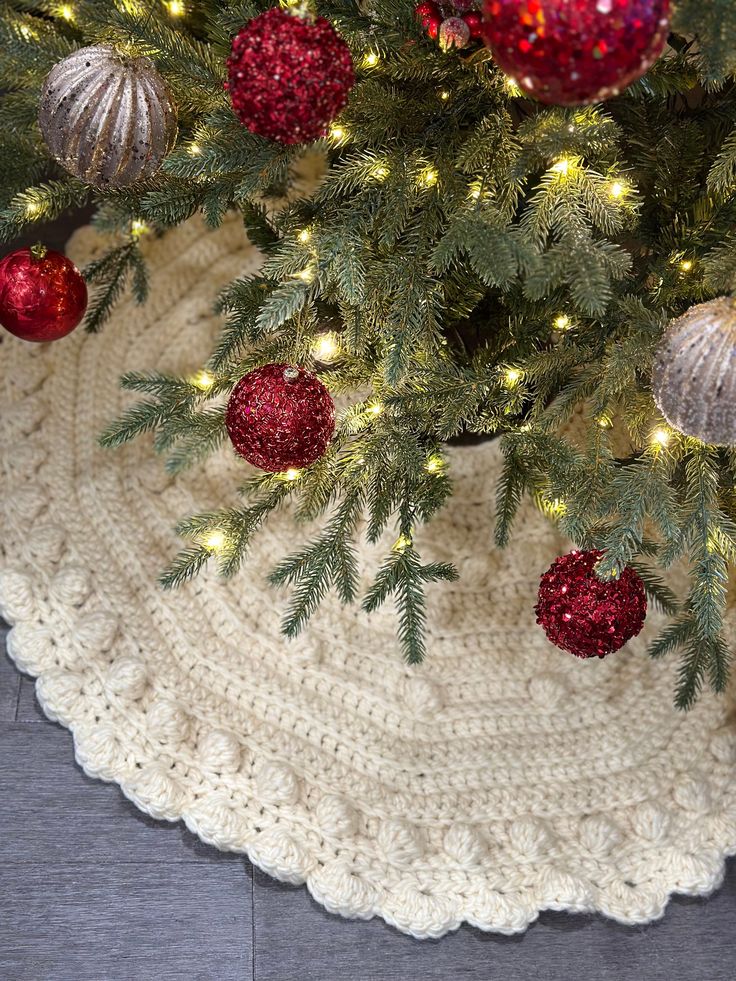 a crocheted christmas tree skirt with ornaments on it