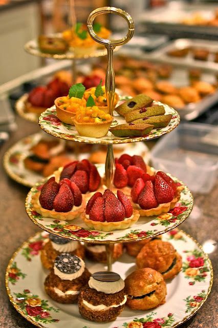 three tiered trays filled with pastries and strawberries on top of each other