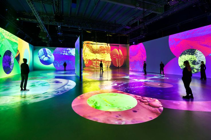 people are standing in front of an art installation with colorful lights on the walls and floor