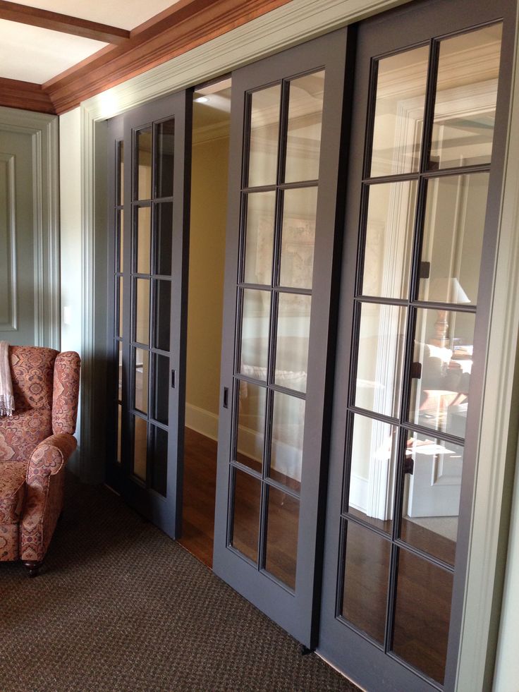 a living room filled with furniture next to two french doors and a chair in front of it