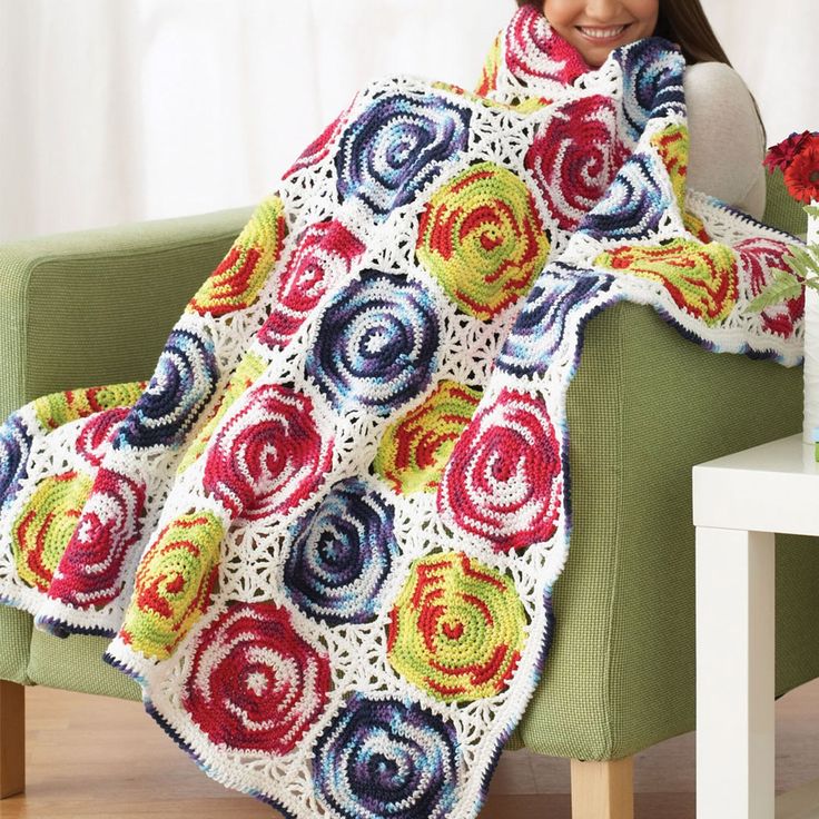 a woman sitting on a chair holding a crocheted blanket