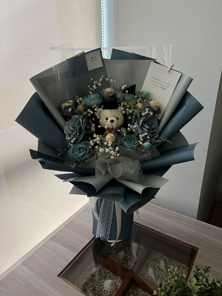 a bouquet of flowers with a teddy bear in it