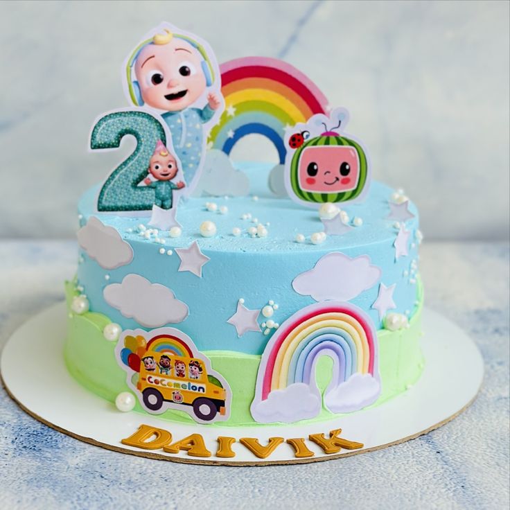 a birthday cake with two children's characters on it and a rainbow in the background