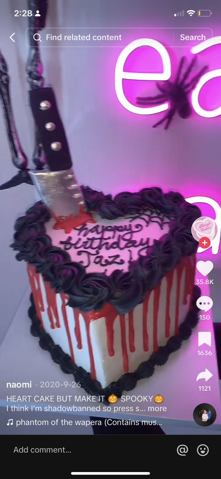 a heart shaped cake with black icing and pink frosting on the top is displayed in front of a purple neon sign