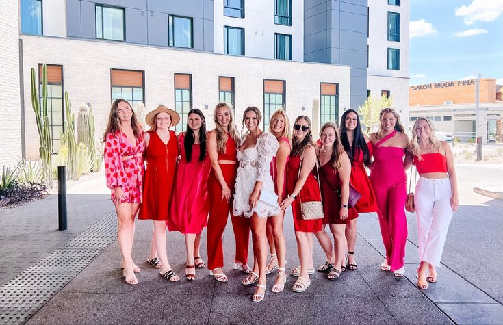 a group of women standing next to each other in front of a tall white building