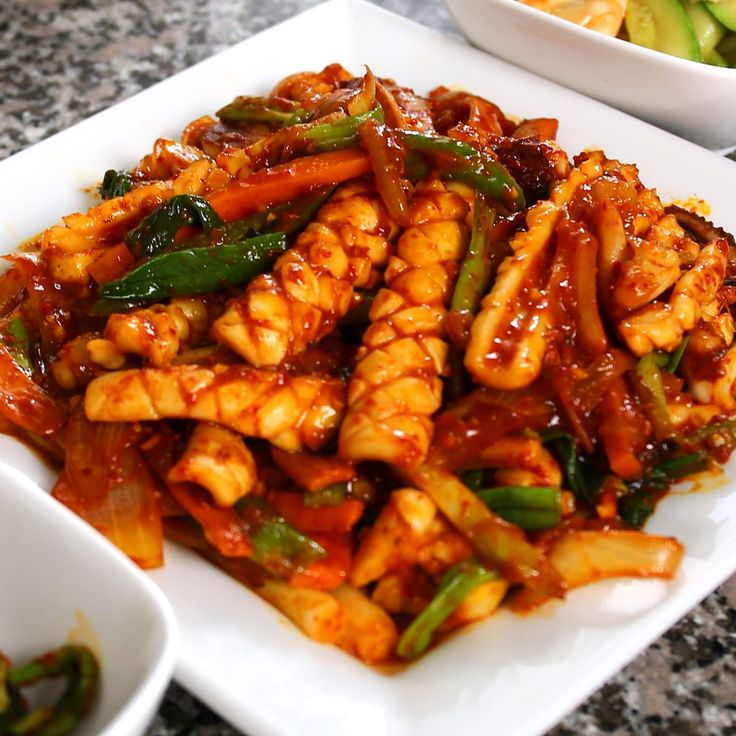 a white plate topped with chicken and veggies next to bowls of vegetables on a table