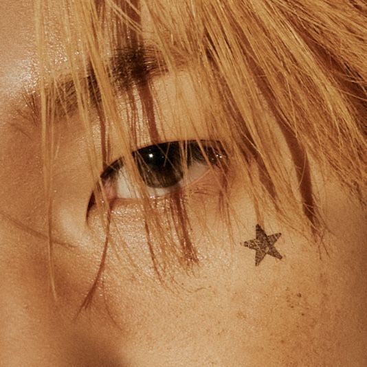 a close up of a person's eye with a star tattoo on their forehead