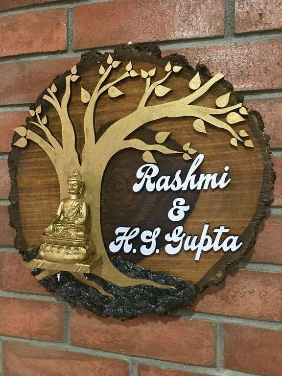 a wooden sign on the side of a brick wall with a buddha statue under a tree