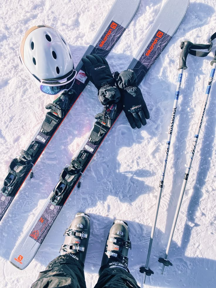 two pairs of skis and poles laying in the snow with their feet up on it