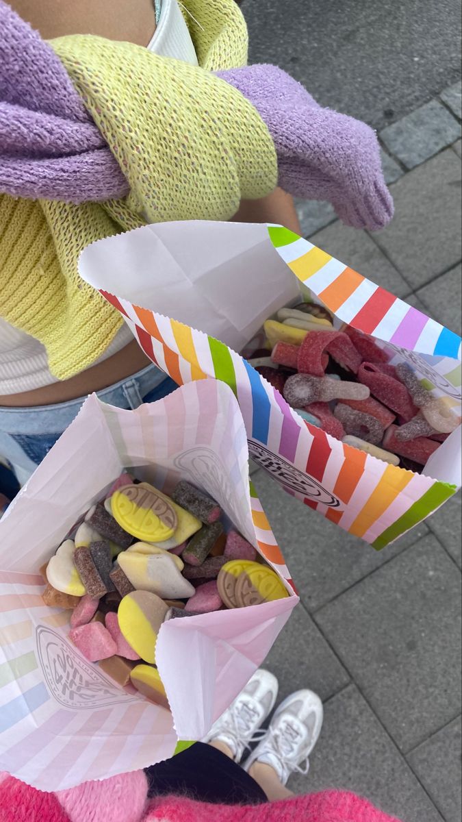 two people holding paper bags filled with candy