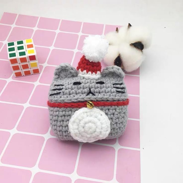 a small crocheted purse with a cat on it next to a stuffed animal