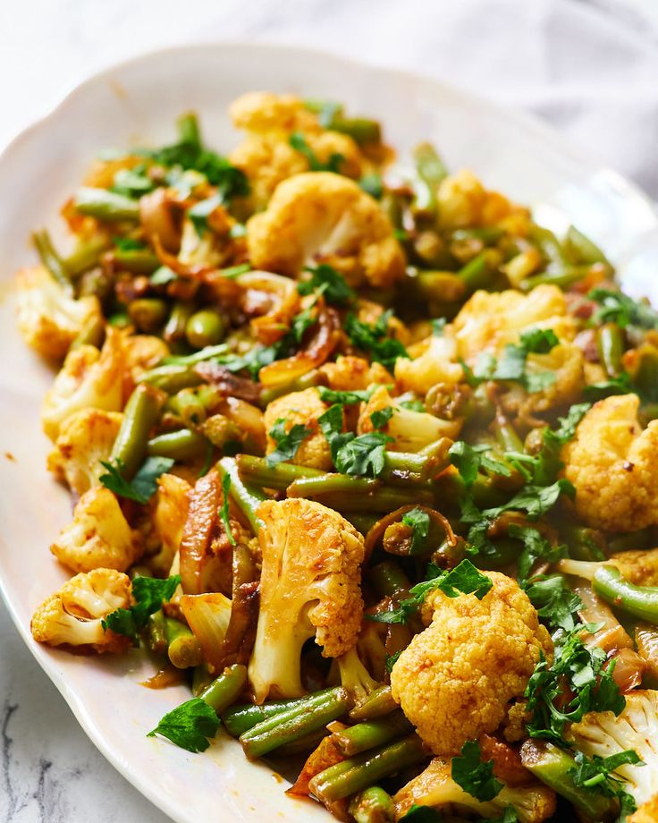 a white plate topped with cauliflower and green beans