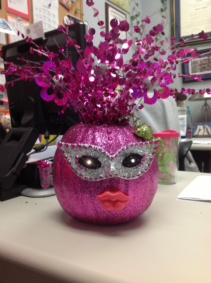 a pink vase filled with purple flowers on top of a table next to a computer desk