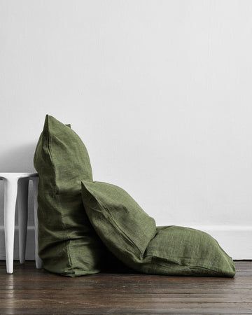 a green pillow sitting on top of a wooden floor next to a white table and chair