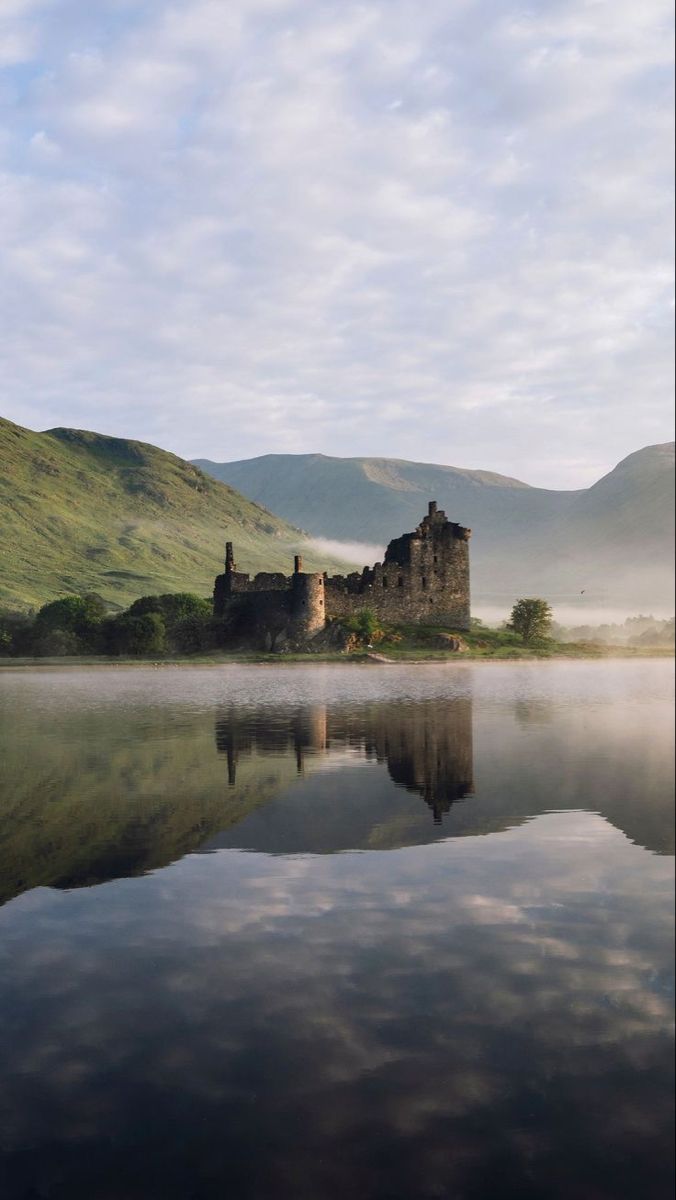 a castle sitting on top of a lake surrounded by mountains