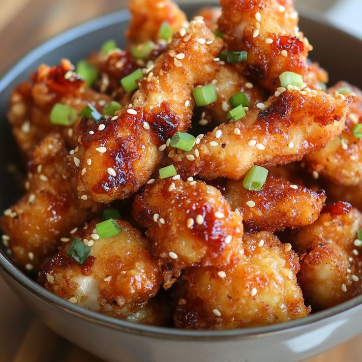 a bowl filled with fried chicken and sesame seeds