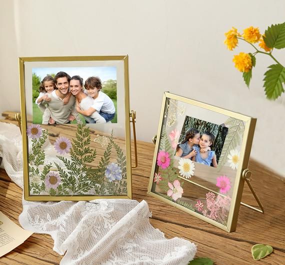 there are two pictures on the table with flowers